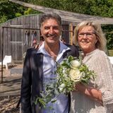 Ein Mann und eine Frau stehen vor einer Holzhütte.