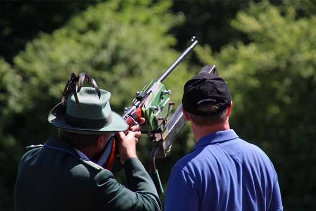 Ein Mitglied des Schützenvereins legt das Gewehr an, um auf einen Holzvogel zu schießen.