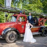 Das Brautpaar Maren und Miro Volkmer steht an einem historischen Einsatzfahrzeug der Feuerwehr Herten.