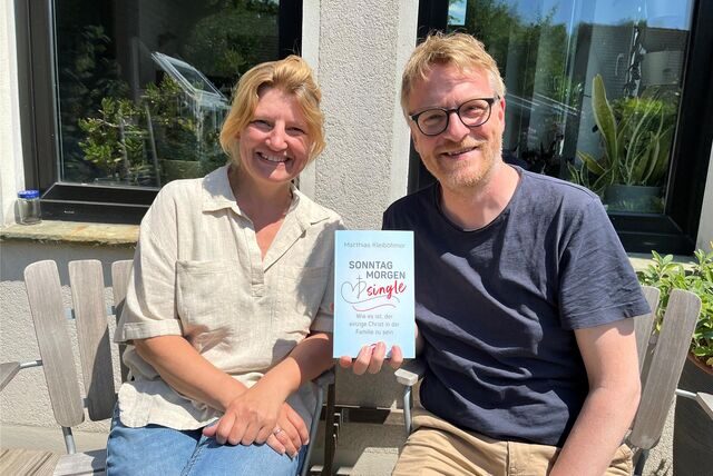 Die Eheleute Kleiböhmer lächeln in die Kamera und er hält das Buch hoch.