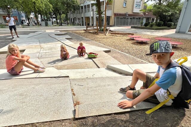 Die Kinder Luca, Laura, Emily und Lilly sitzen auf dem trockenen Brunnen