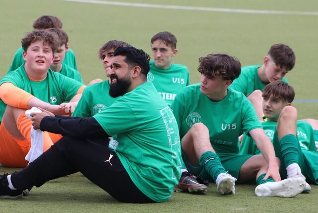Spieler und Trainer von Wethamrs U15 sitzen auf dem Boden.
