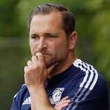 Claudio Marzolla schaut mit skeptischen Blick aufs Spielfeld und hält mit seiner Hand sein Kinn.