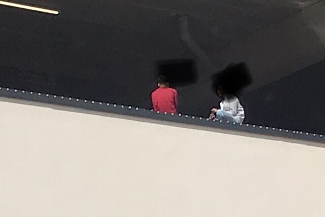 Zwei Jugendliche machen Pause auf dem Parkdeck 1 des Einkaufszentrums Neue Mühle in Unna, haben sich dafür auf die Brüstung gesetzt.