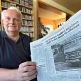 Werner Sander in seinem Wohnzimmer mit einer Zeitung in der Hand, in der ein Artikel über ihn steht. Titel: Vor 55 Jahren – Badebus kutschiert Kinder in den Ferien ins Löhnbad.