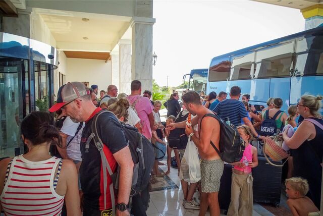 Touristen warten vor ihrem Hotel auf der griechischen Insel Rhodos auf den Einstieg in Busse, um die Insel wegen schwerer, tagelanger Waldbrände zu verlassen.