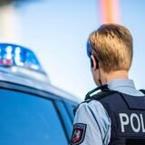 Eine Polizistin steht vor einem Streifenwagen (Symbolbild).