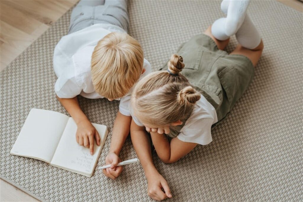 zwei kinder lesen und schreiben auf einem teppich