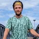 Pascal Weiß steht mit seinem Fahrrad vor einer Brücke.