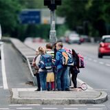 Eine Schülergruppe testet einen eventuellen, künftigen Schulweg und steht auf einer Verkehrsinsel inmitten der viel befahrenen Miquelallee.