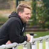 Benedikt Kuhne lehnt lässig über dem Geländer, hat eine Tasse in der Hand.