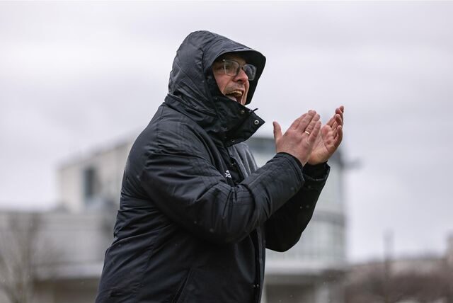 Benjamin Hartlieb trägt eine Kapuze im Regen und klatscht in die Hände.
