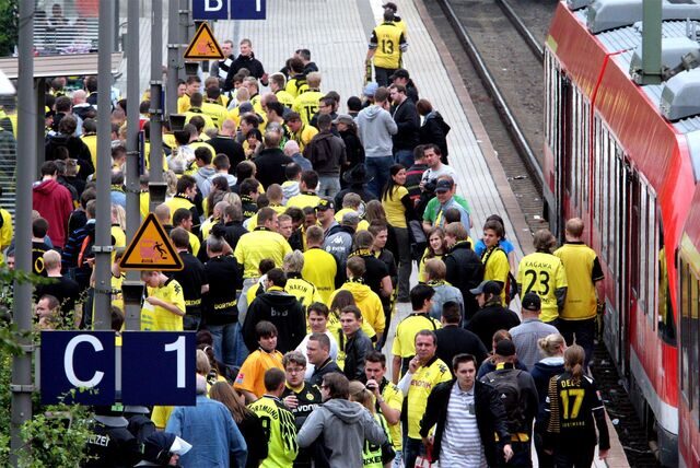 Fans von Borussia Dortmund steigen gerade aus einem Zug aus, der am Bahnhof des Stadions, Signal Iduna Park, hält.
