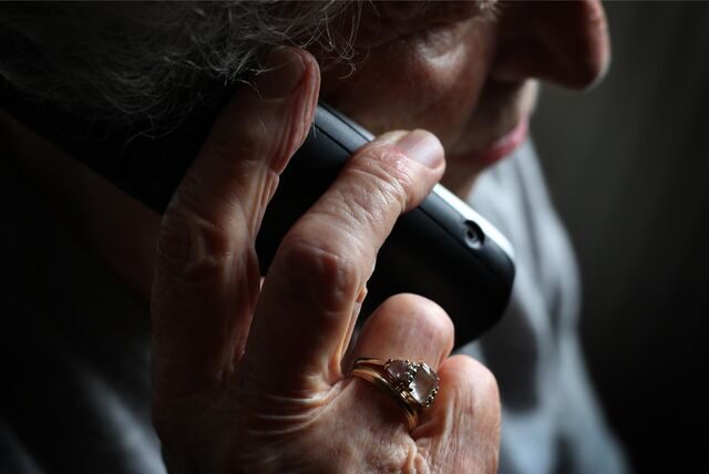 Eine Seniorin hält einen Telefonhörer.