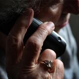 Eine Seniorin hält einen Telefonhörer.
