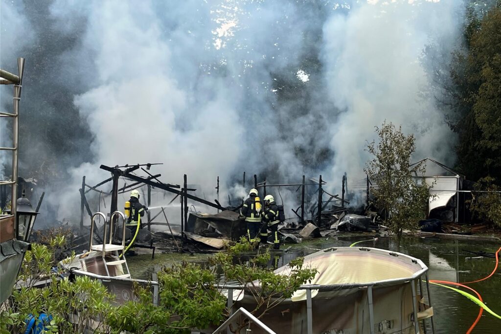 Feuerwehrleute löschen einen Gartenlaubenbrand. Feuerwehrleute löschen einen Gartenlaubenbrand.
