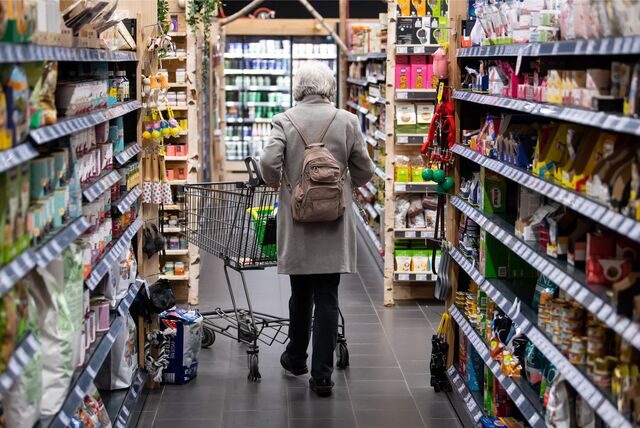 Eine Frau läuft mit ihrem Einkaufswagen durch einen Supermarkt.