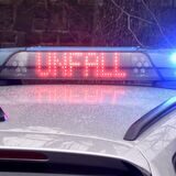 Das Symbolbild zeigt einen Polizeiwagen mit eingeschaltetem Blaulicht, auf dem in roter Schrift das Wort Unfall leuchtet