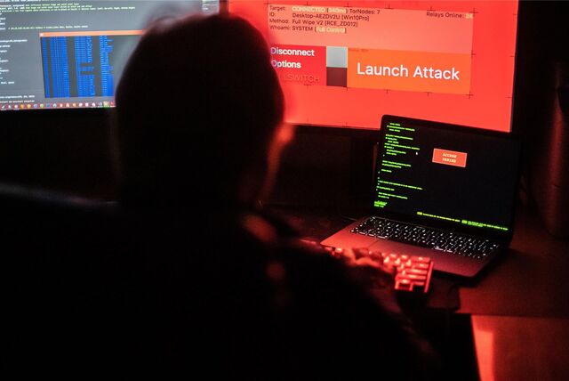 Ein Mann sitzt vor Bildschirmen, die Hacker-Programme und eine fiktive Fernlösch-Software zeigen.