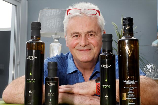 Dimitrios Mitrenas zeigt Flachen von dem Olivenöl, das er produziert und verkauft.