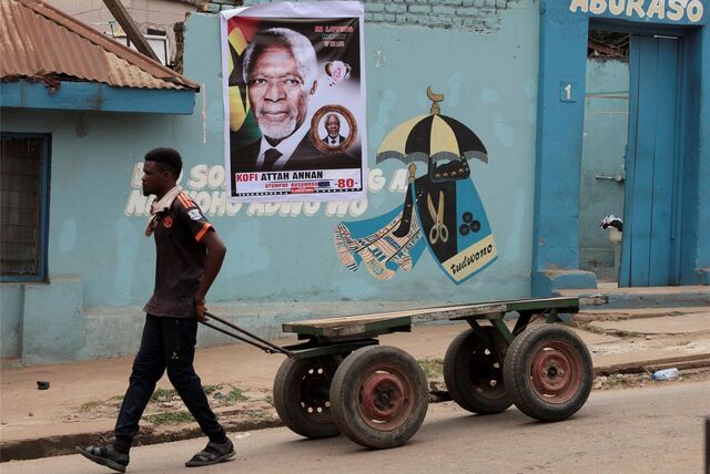 Ghana, Kumasi: Ein Mann zieht einen Anhänger an dem Haus der Familie des ehemaligen UNO-Generalsekretärs Kofi Annan vorbei, an dem ein Plakat mit einem Foto von Annan hängt. Der ghanaische Diplomat, geboren in Kumasi, ist am 18.08.2018 im Alter von 80 Jahren in der Schweiz gestorben
