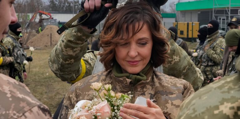 Ein Soldat hält einen Helm als Hochzeitskrone während der Hochzeitszeremonie für die Mitglieder der ukrainischen Territorialen Verteidigungskräfte Lesia Ivashchenko und Valerii Fylymonov, an einem Kontrollpunkt in Kiew.