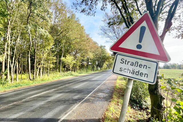 Ein „Achtung“-Schild auf der L673. Darunter die Aufschrift: „Straßenschäden“.
