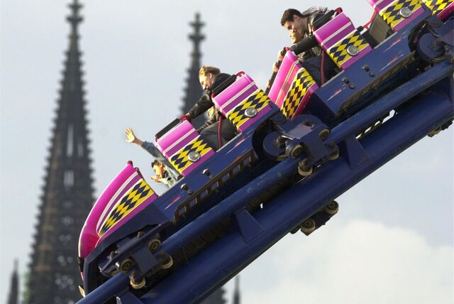 Besucher der Herbstkirmes in Köln in einem Fahrgeschäft, vor der Kulisse des Kölner Doms.