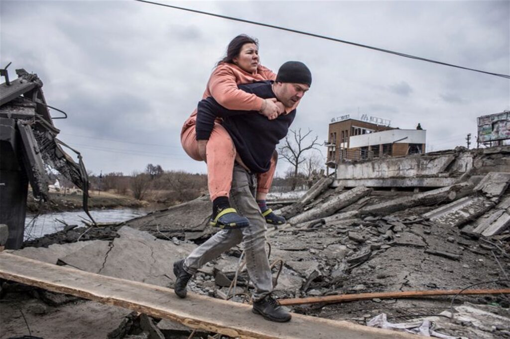 Größtmögliches Leid der Zivilbevölkerung: Ein Mann trägt eine Frau durch Trümmer. Sie sind auf der Flucht aus der ukrainischen Stadt Irpin. 