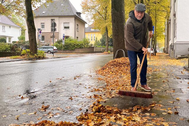 Wolfgang Frenser fegt das Laub von einem Bürgersteig an der Hertingerstraße in Unna.