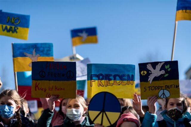 Demonstranten halten Schilder mit den Farben der ukrainischen Flagge in die Luft.