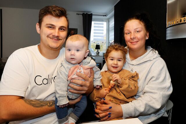 Die vierköpfige Familie: Vater, 3 Monate altes Baby, die zweieinhalb-jährige Schwester und die Mutter. Sie lächeln in die Kamera.