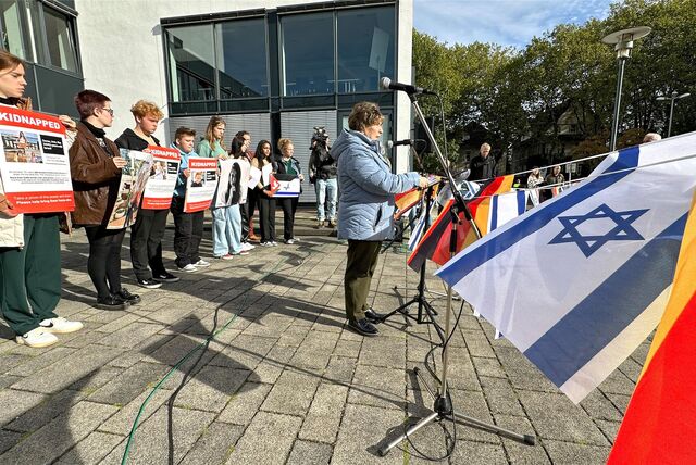 Eine Frau steht vor dem Kreishaus Unna am Rednerpult. Links von ihr halten mehrere Menschen Plakate in den Händen, auf denen „Kidnapped“ zu lesen ist. Und auf einer Leine rechts von ihr sind mehrere deutsche und israelische Fahnen gespannt.