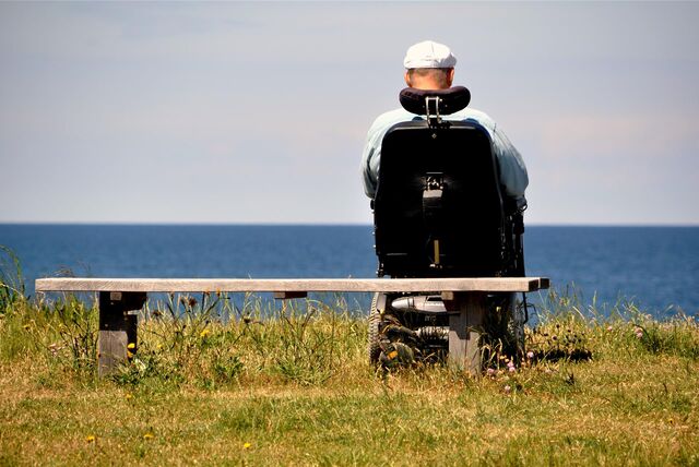 Mann sitzt im Rollstuhl und schaut aufs Meer
