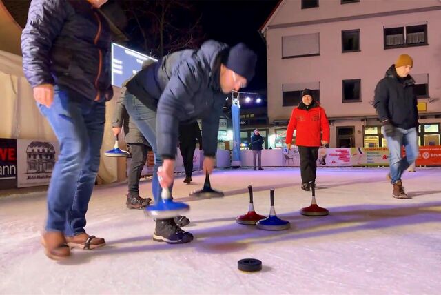 Männer auf der Eisfläche halten Eisstöcke in der Hand