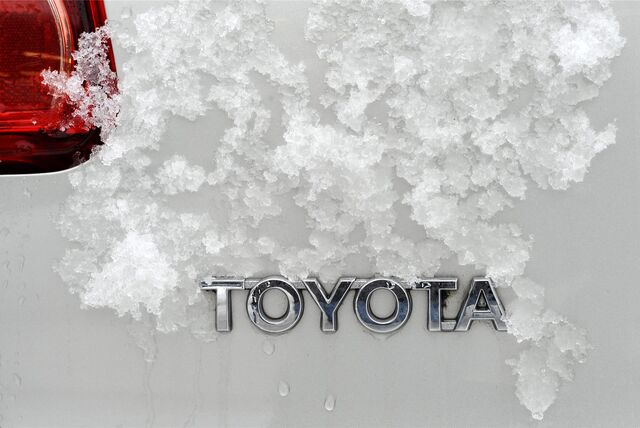 Schnee liegt über dem Schriftzug „Toyota“ auf einem weißen Auto.