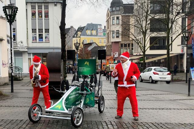 Lars Wockenfuss und Stefan Käßner haben sich am 6. Dezember 2023 als Weihnachtsmänner verkleidet. Auf dem Postplatz in der Schwerter Innenstadt stehen sie und machen Musik. Der eine spielt Saxophon, der andere singt.