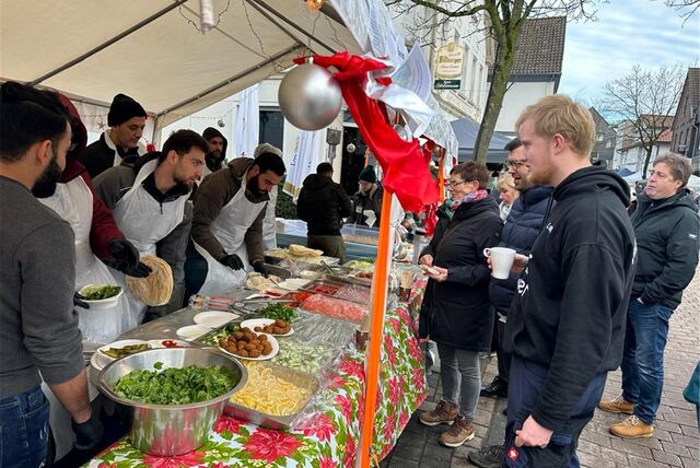 An einem Stand auf dem Weihnachtsmarkt in Bork verteilen Menschen, die in der Borker Zeltstadt leben, selbst gemachte Falafel.