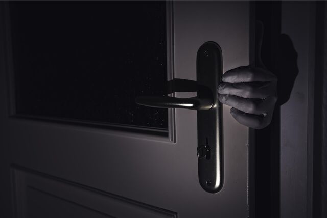 Ein Einbrecher mit Handschuhen verschafft sich Zutritt zu einer Wohnung.