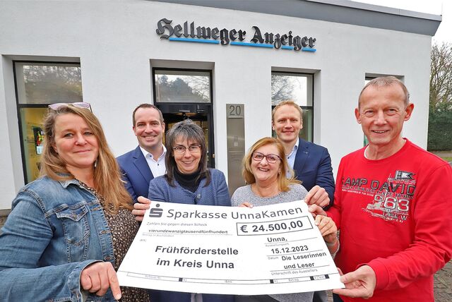Mehrere Personen halten vor dem Servicecenter des Hellweger Anzeigers in Unna einen Spendenscheck zugunsten der Frühförderstelle im Kreis Unna.