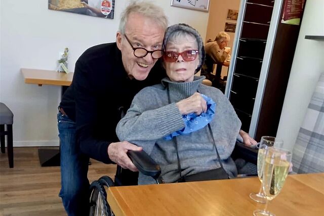 Wichart von Roëll beugt sich über Ingrid Steeger, die im Rollstuhl sitzt.