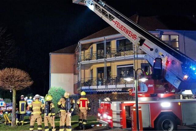 Eine Löschgruppe der Feuerwehr steht vor einem Wohnheim. Die Drehleiter ist ausgefahren und zeigt in Richtung des Hauses.