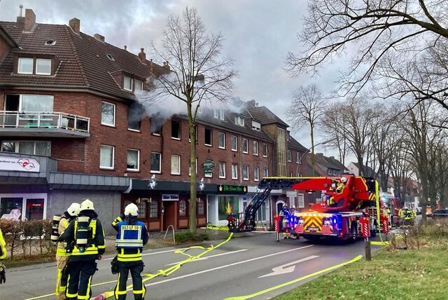 Aus einem Mehrfamilienhaus dringt Rauch, davor steht ein Einsatzfahrzeug der Feuerwehr.