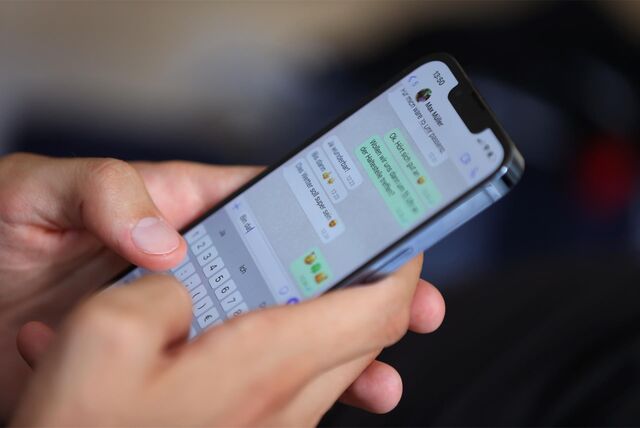 Zwei Hände, die auf einem Smartphone eine WhatsApp-Nachricht tippen.