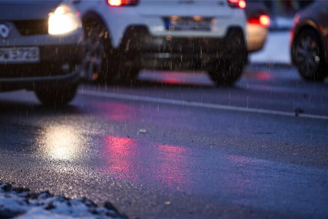 Autos fahren am Morgen bei Regen und Schneeglätte in Richtung Innenstadt.