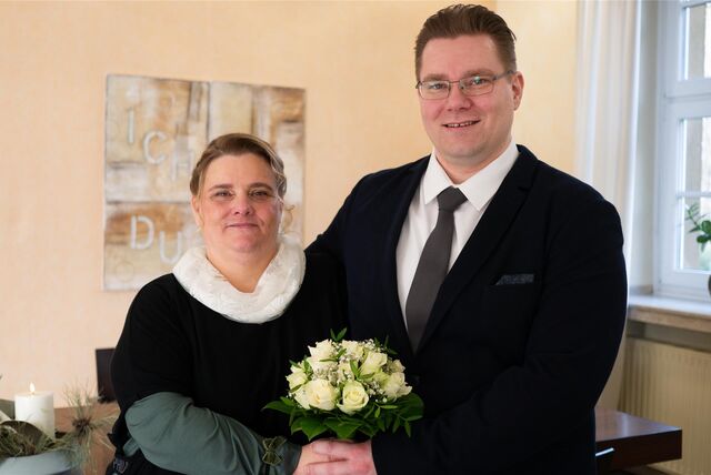 Ein Brautpaar mit Strauß steht in einem Trauzimmer.