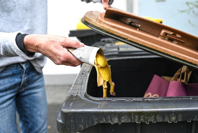 Ein Mann wirft Biomüll in eine Abfalltonne