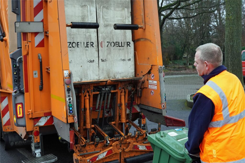 Ein Mitarbeiter der Entsorgungsbetriebe bringt eine Mülltonne zum Entladen zum Müllwagen. Ein Mitarbeiter der Entsorgungsbetriebe bringt eine Mülltonne zum Entladen zum Müllwagen.