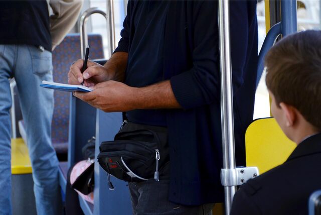 Ein Kontrolleur in einem Bus notiert sich etwas.