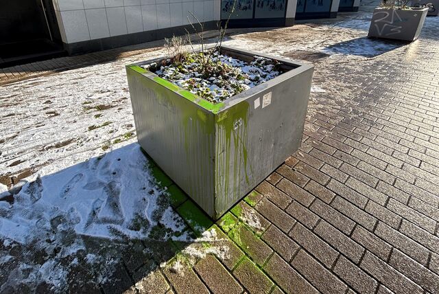 Ein grauer Pflanzkübel in der Kamener Innenstadt, der mit grüner Farbe beschmiert wurde.